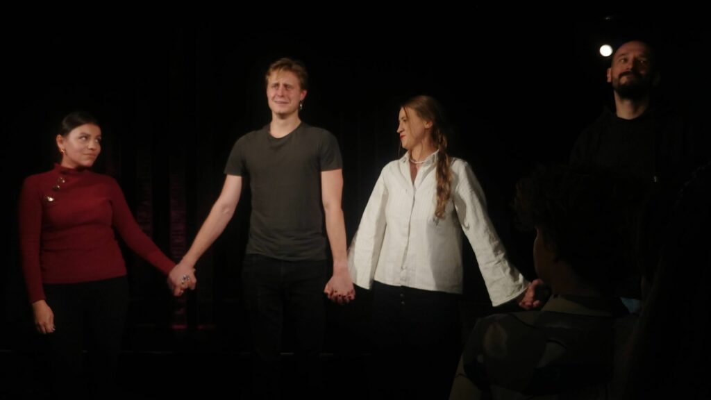 Teatr Forum, zakończenie, postacie stoją i trzymają się za ręce, uśmiechają się z wyjątkiem skwaszonej miny Alex.